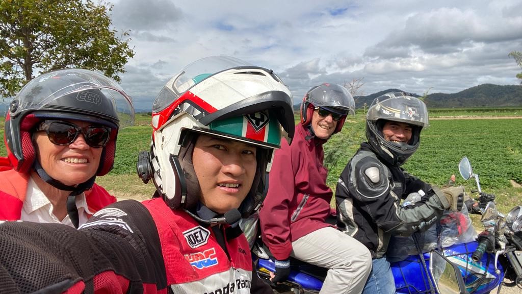 Helmeted riders by green fields on a Nha Trang to Da Lat Easy Rider tour
