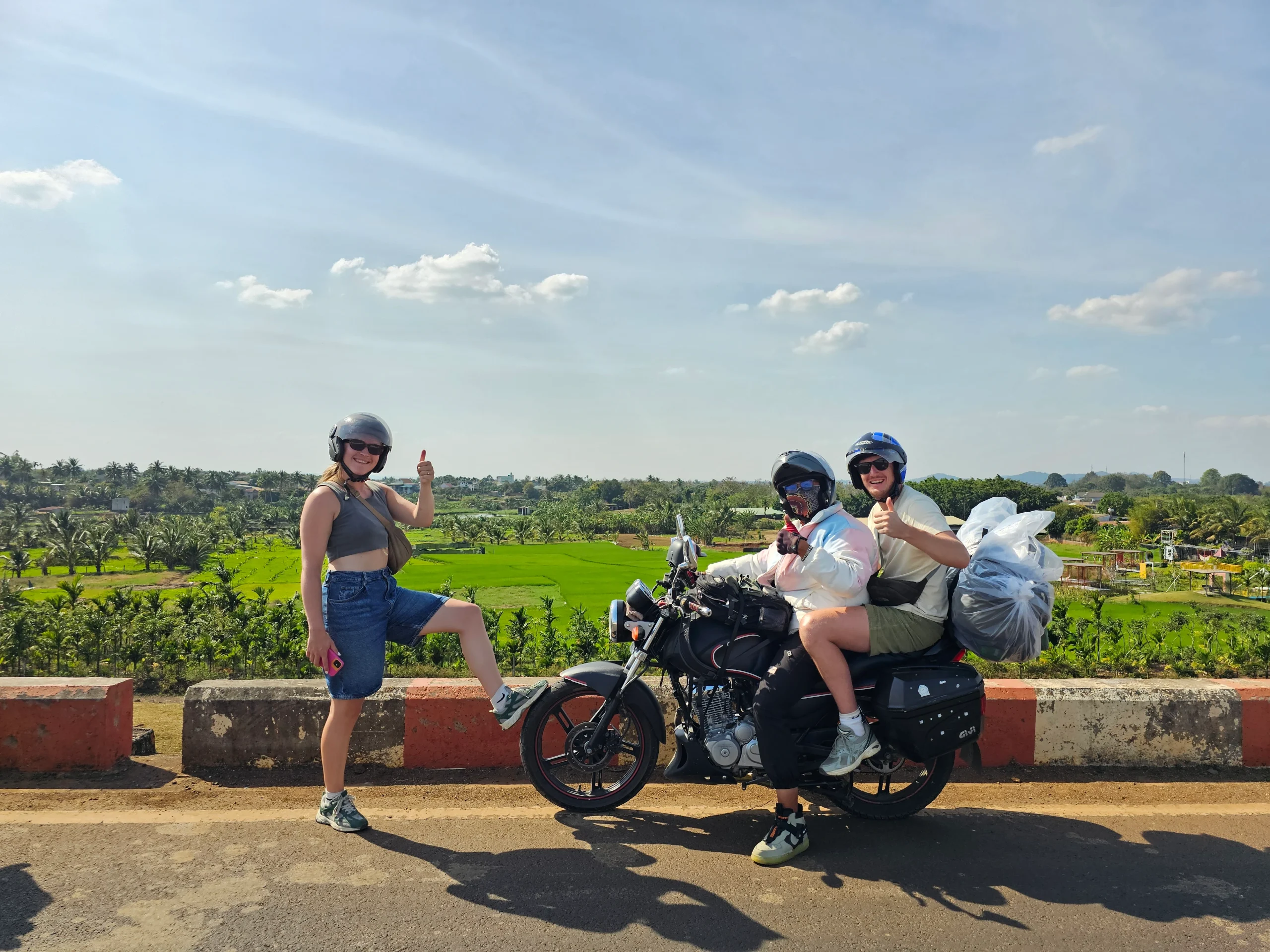 Helmeted travellers and a local guide beside a motorbike on Vietnam Easy Rider tours