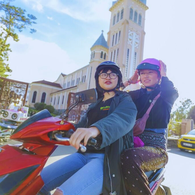 Two helmeted travellers in front of Da Lat Cathedral during an Easy Rider city tour