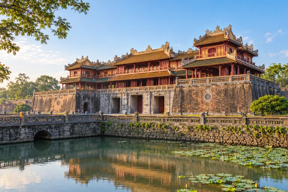 Hue Imperial City-inspired gate with tiled roof pavilions beside a calm moat